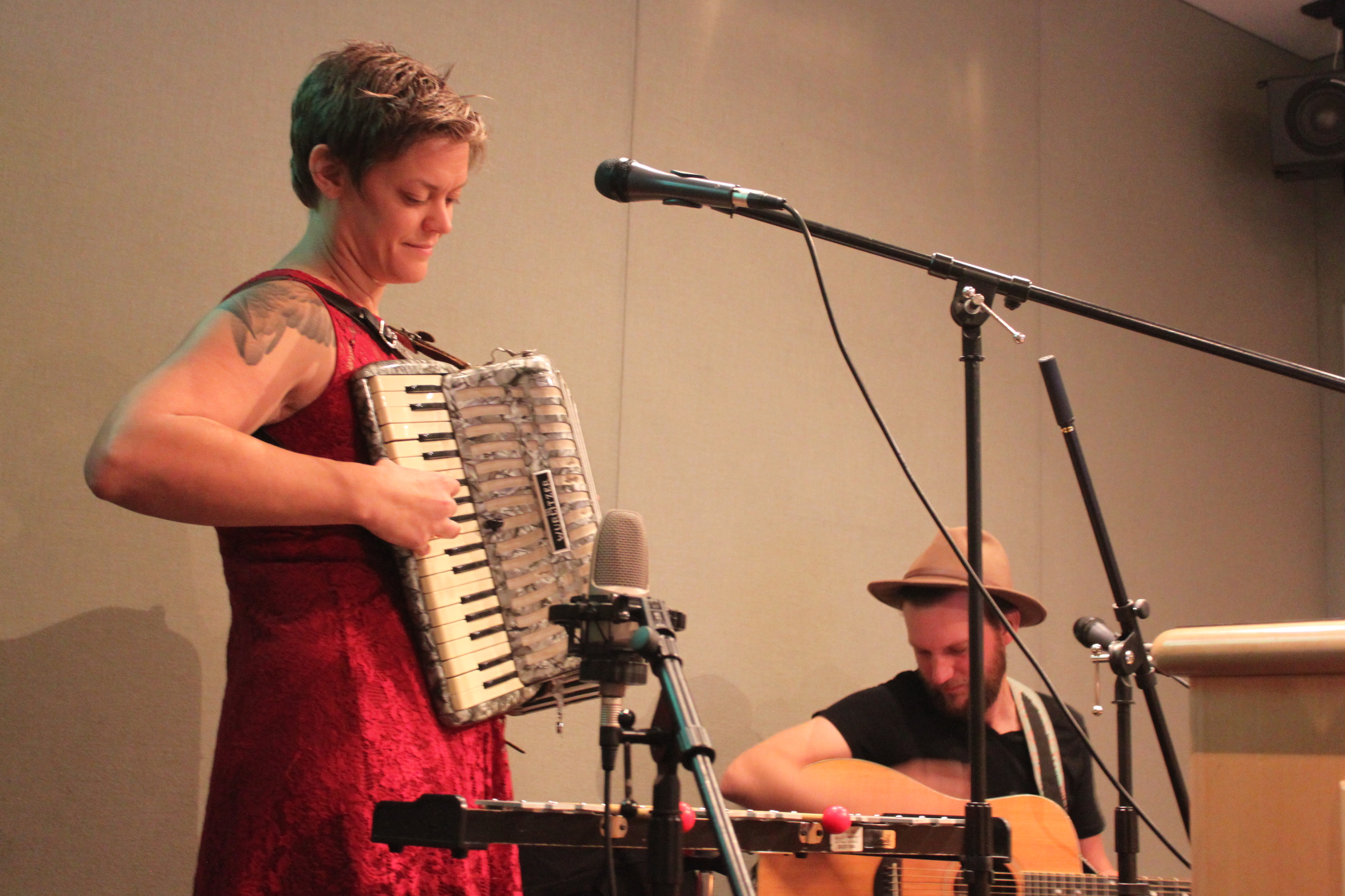 An adult playing an accordion and an adult holding a guitar in a radio studio