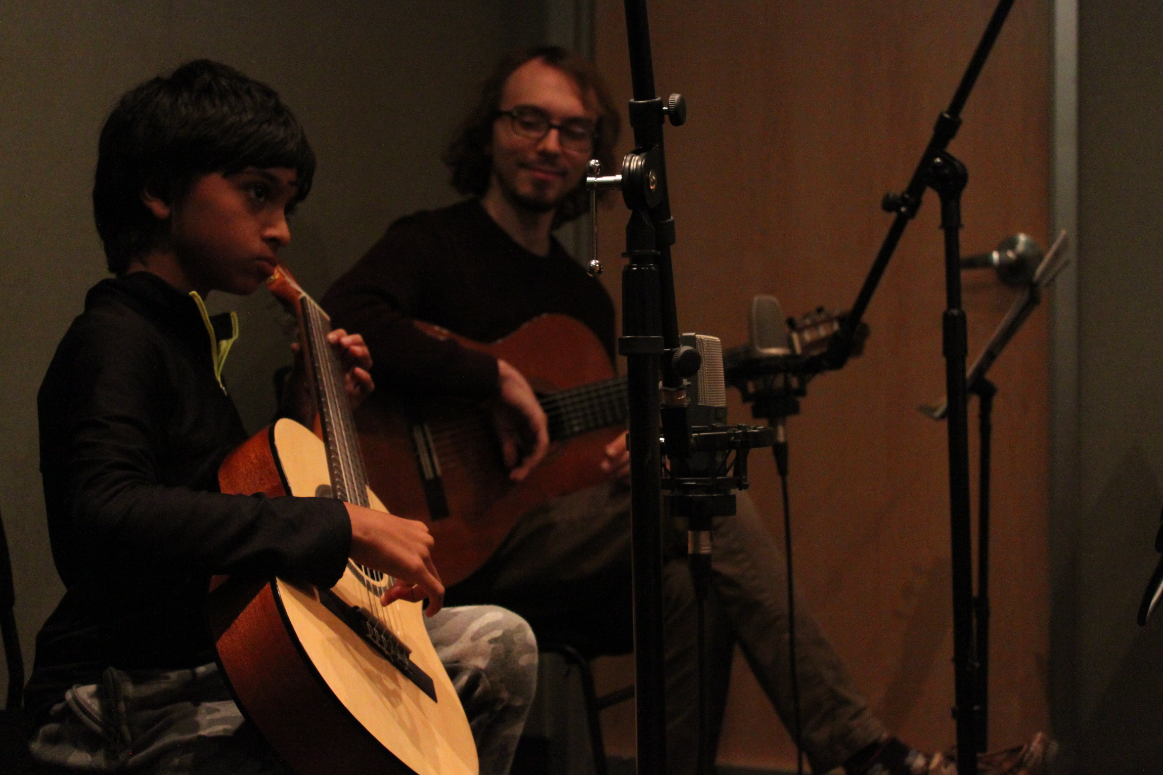 Youth playing guitar and adult holding a guitar in a radio studio