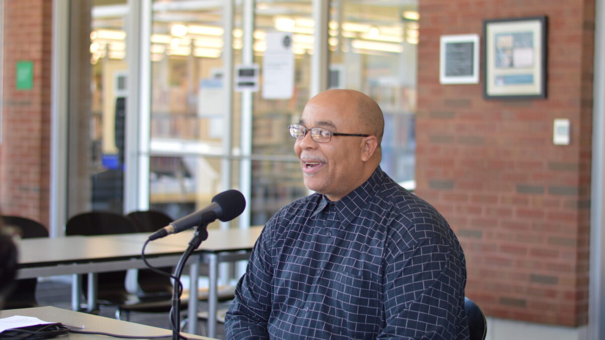 Adult speaking into a microphone on a brown table
