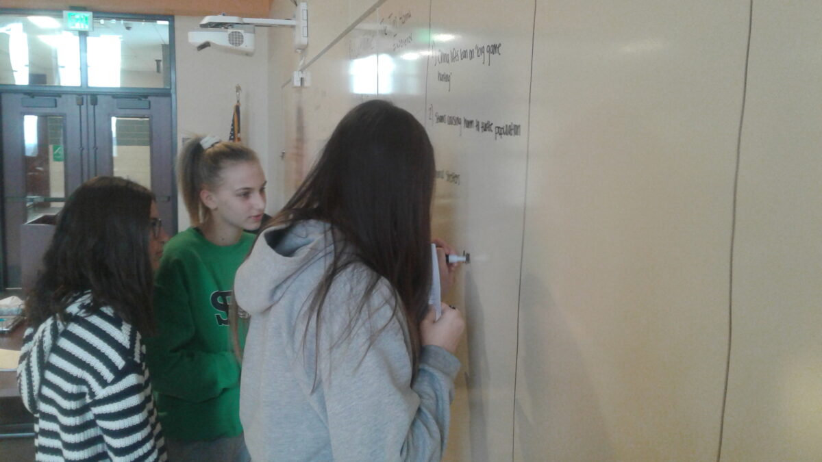 Three youth writing on a whiteboard