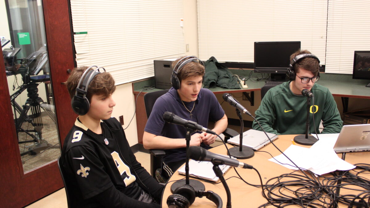 Three teens wearing headphones speaking into microphones