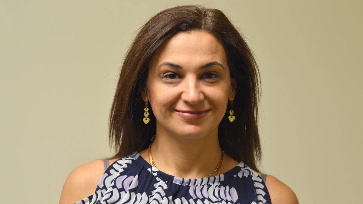 Adult with long brown hair and heart shaped earrings smiling in profile