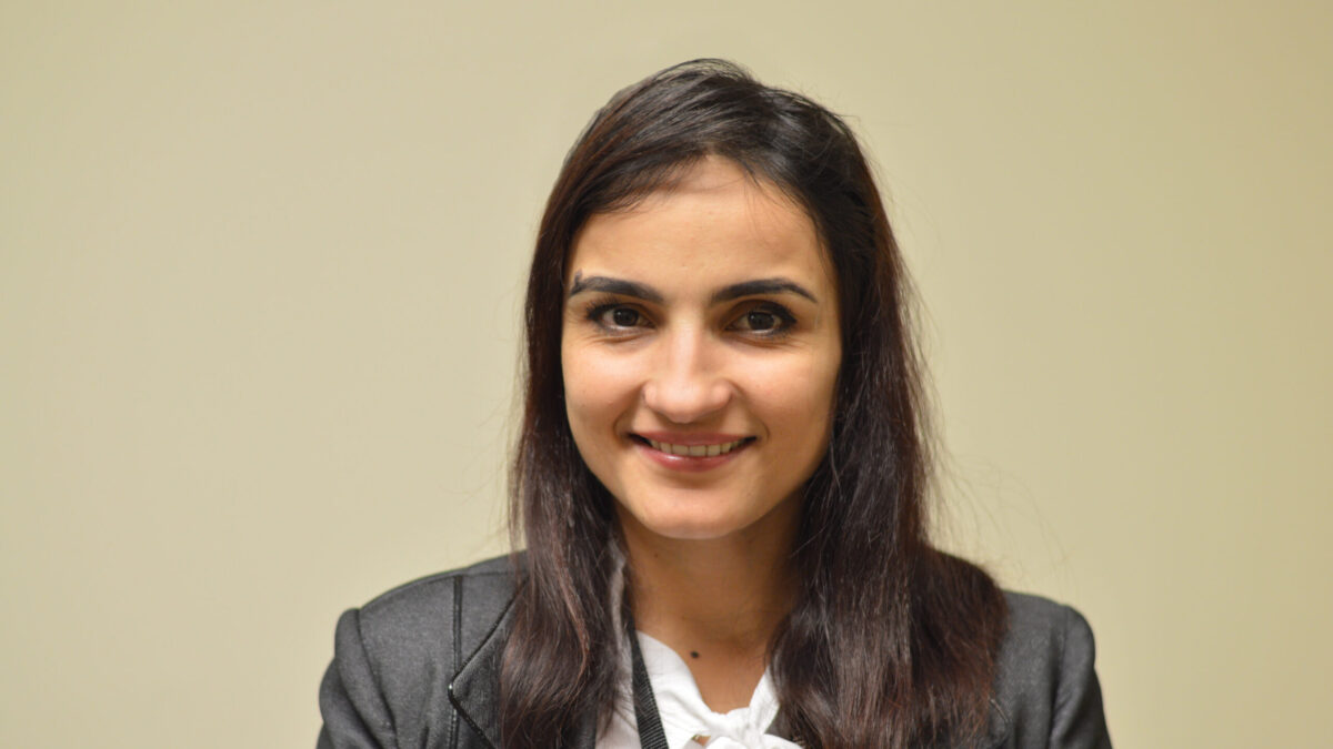 An adult with long dark brown hair smiling in profile