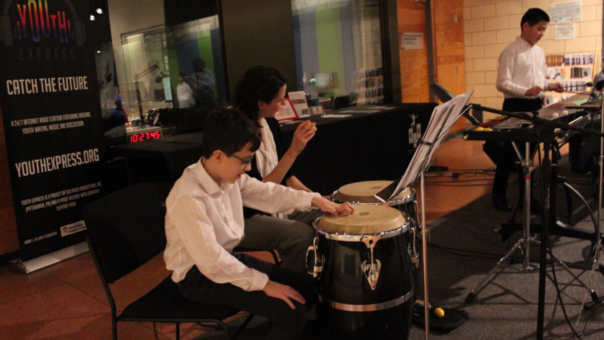 Two youth and one adult performing on congas and marimba