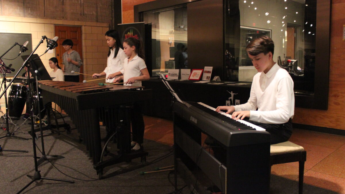 Five youth performing on congas, xylophone, vibraphone, and piano keyboard