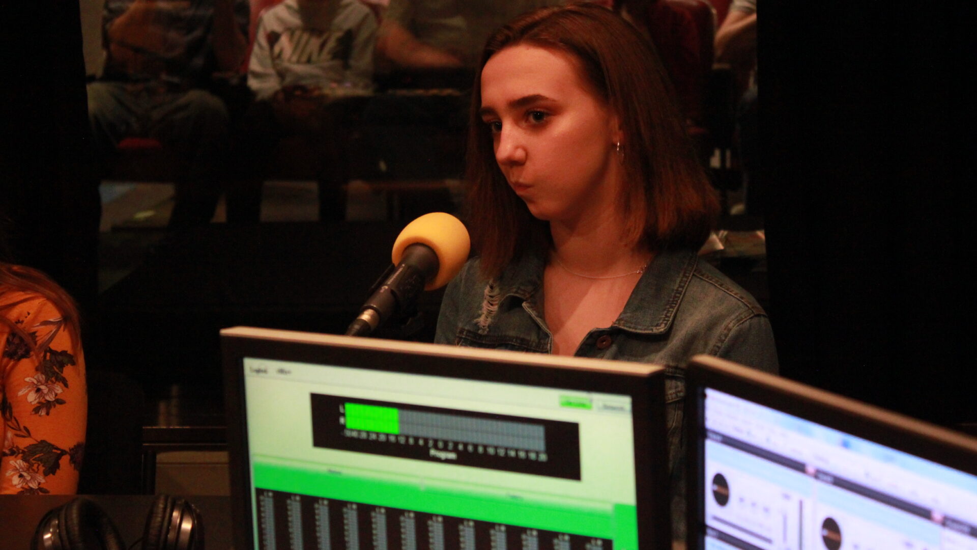Teen sitting behind a microphone in a radio studio
