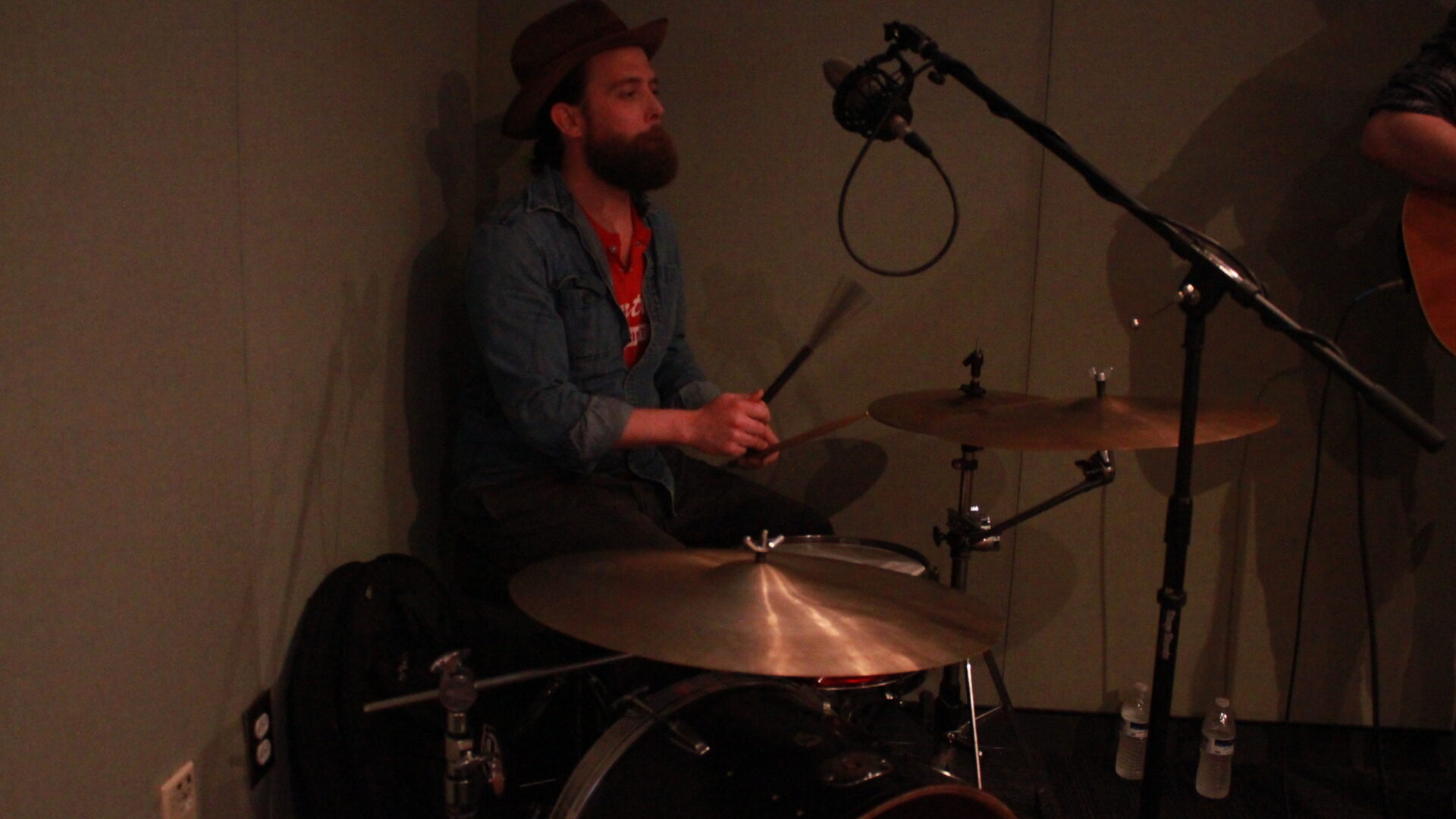Adult playing drum set in a radio studio