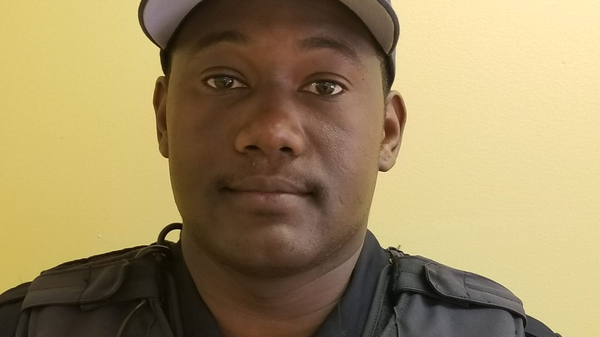 Adult with a black police cap and a police uniform posing in profile
