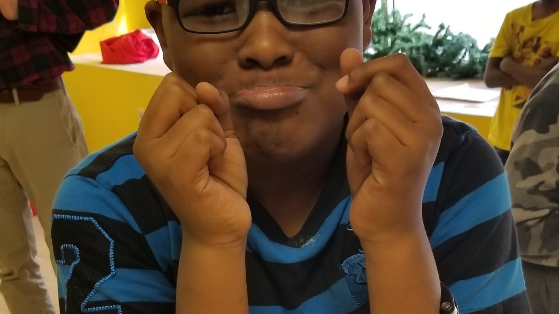 Child wearing glasses and handcuffs with a distressed expression posing in profile