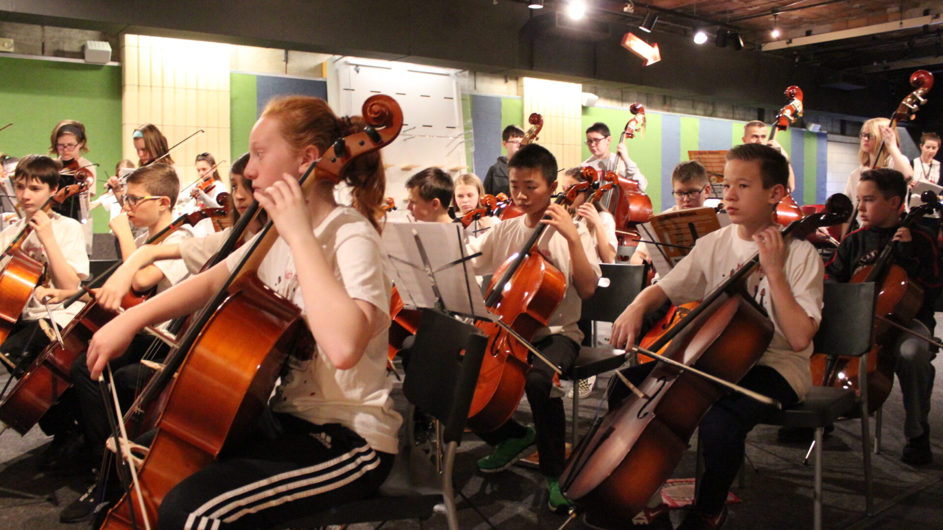 A large group of youth playing string instruments in an orchestra