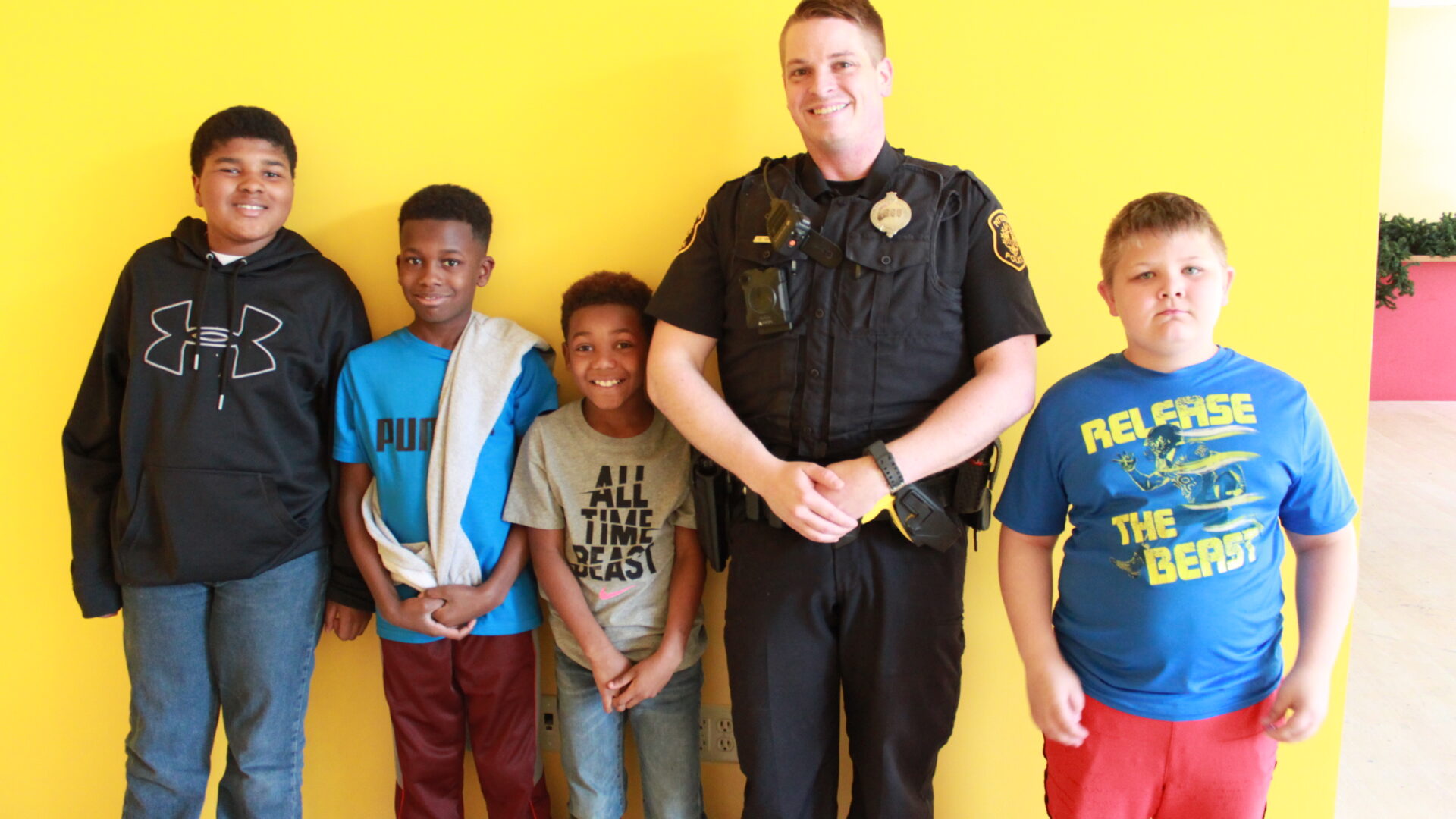 Adult in a police uniform and four children smiling and posing in profile