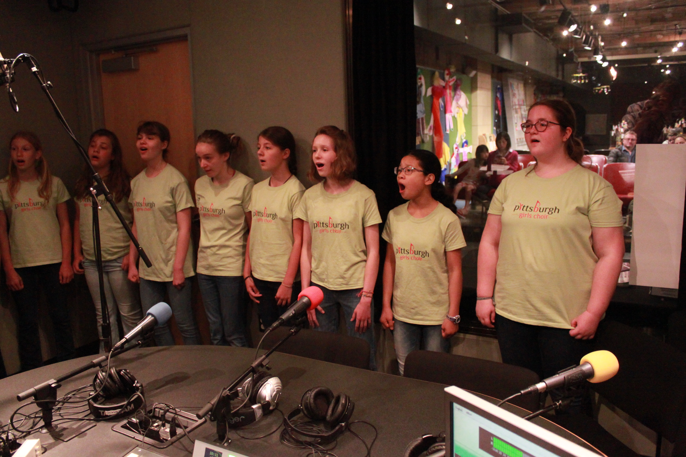 Eight youth singing in front of microphones in a radio studio