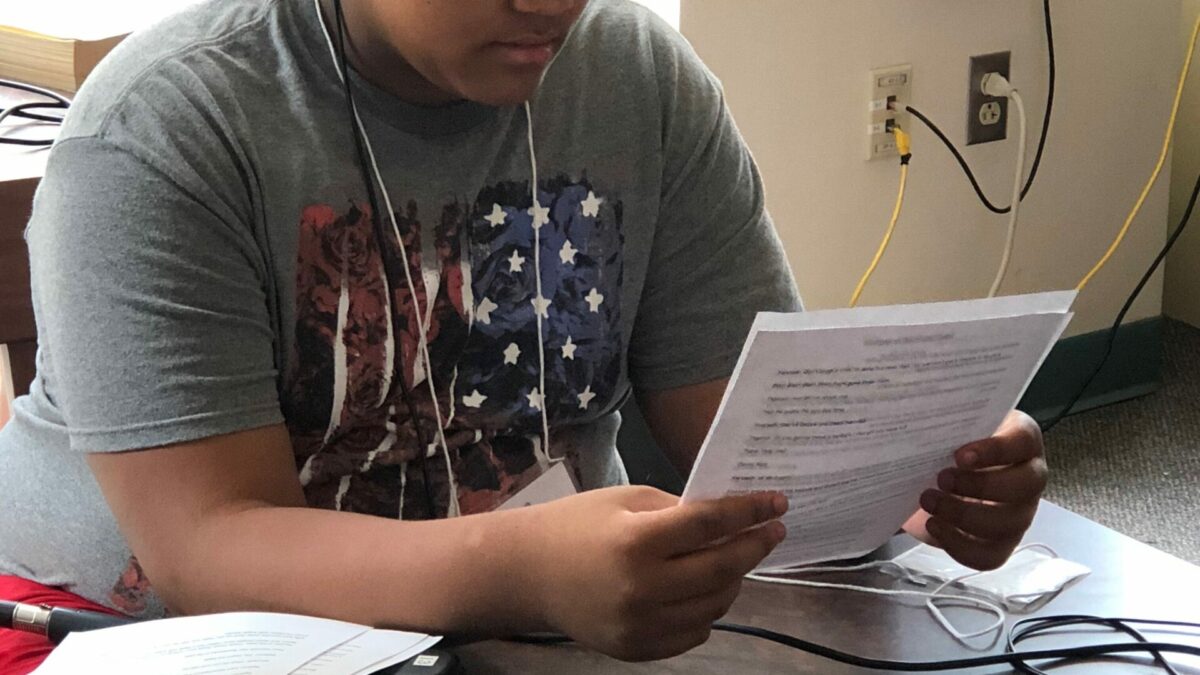 Teen wearing headphones looking down at a piece of paper