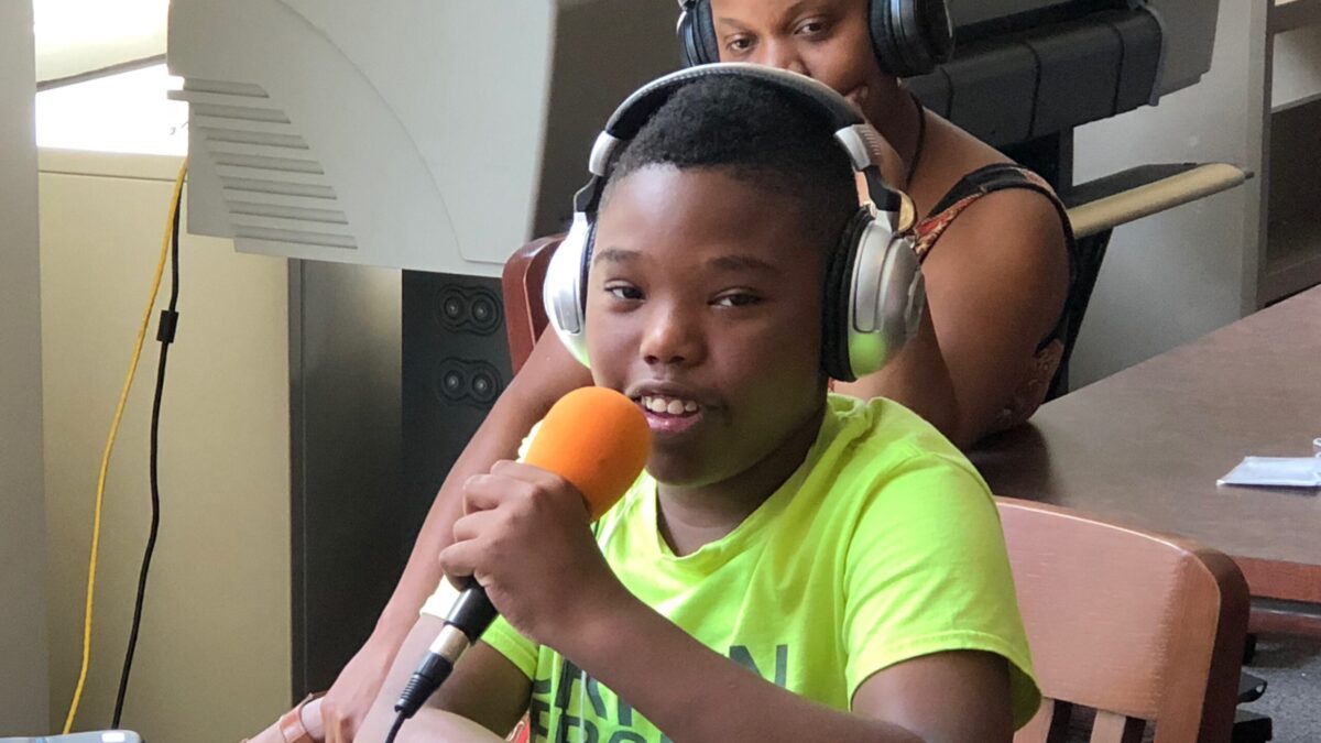 Two youth wearing headphones, one speaking into a microphone