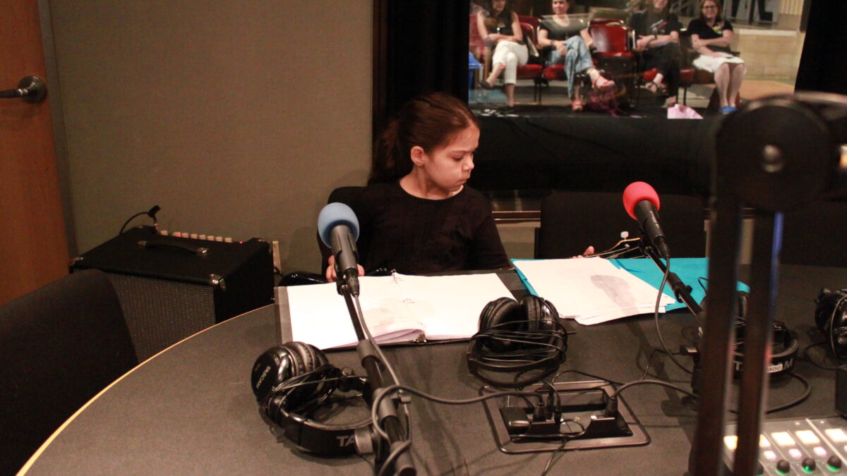 Youth playing bass next to an amp in a radio studio