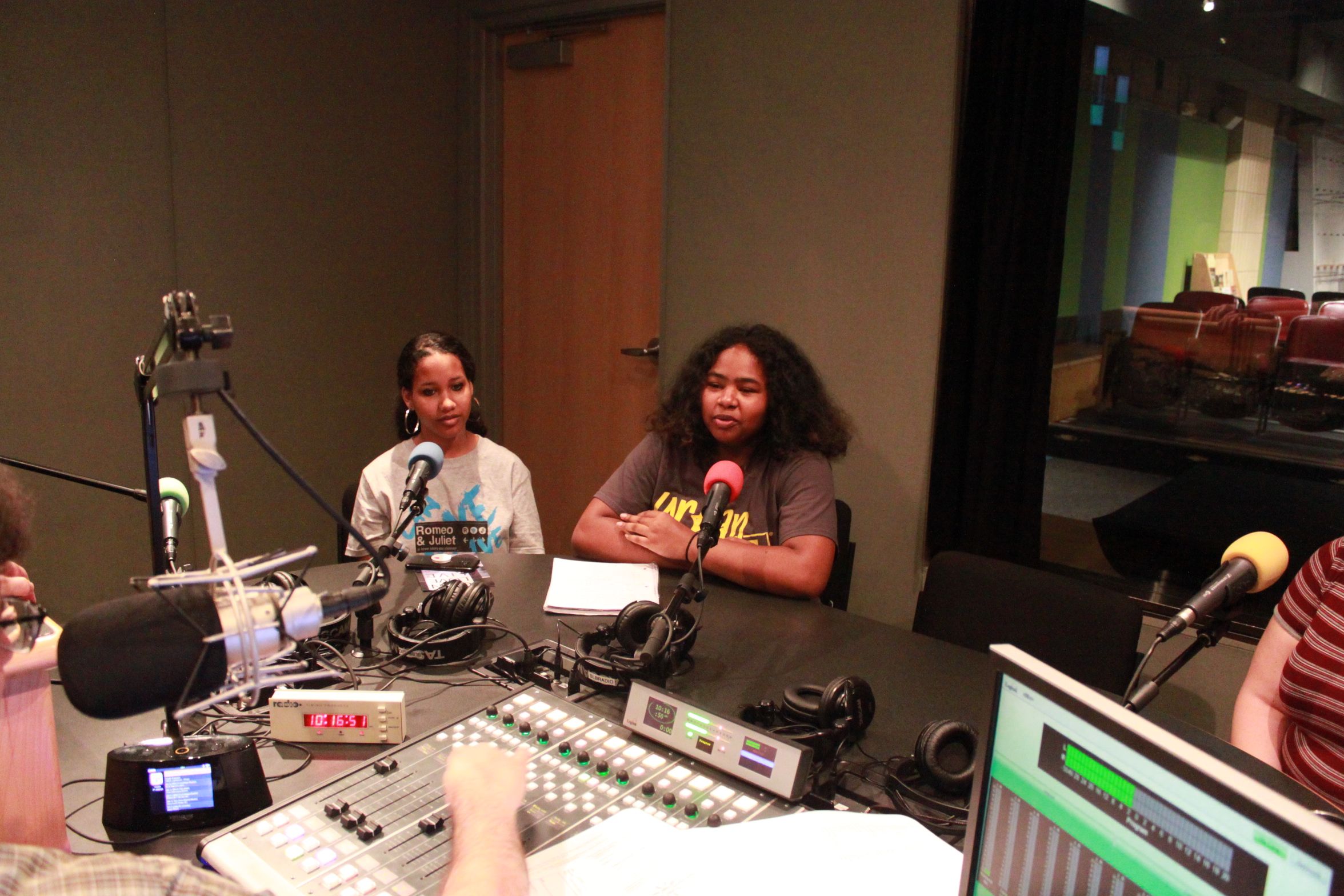 Two teens speaking into microphones being interviewed in a radio studio