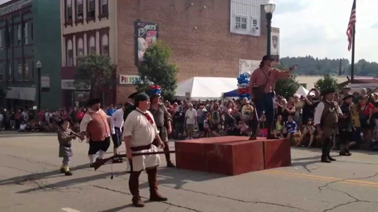 A large crowd watching historical battle reenactors on a city street