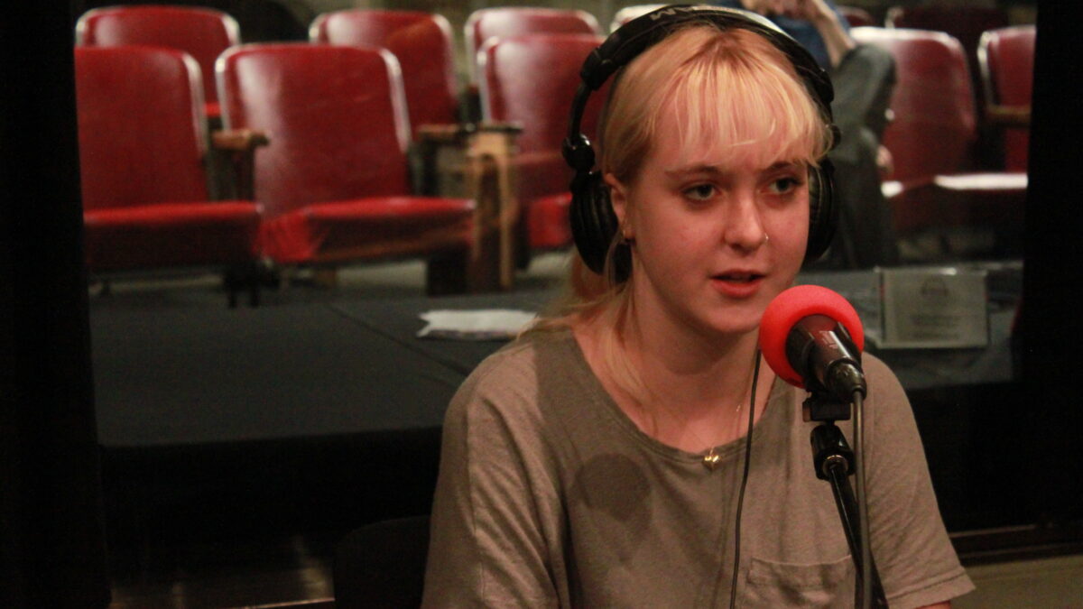 Teen wearing headphones speaking into a microphone in a radio studio