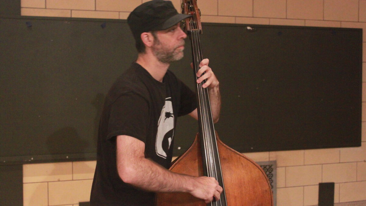 Adult playing upright bass and looking to the right