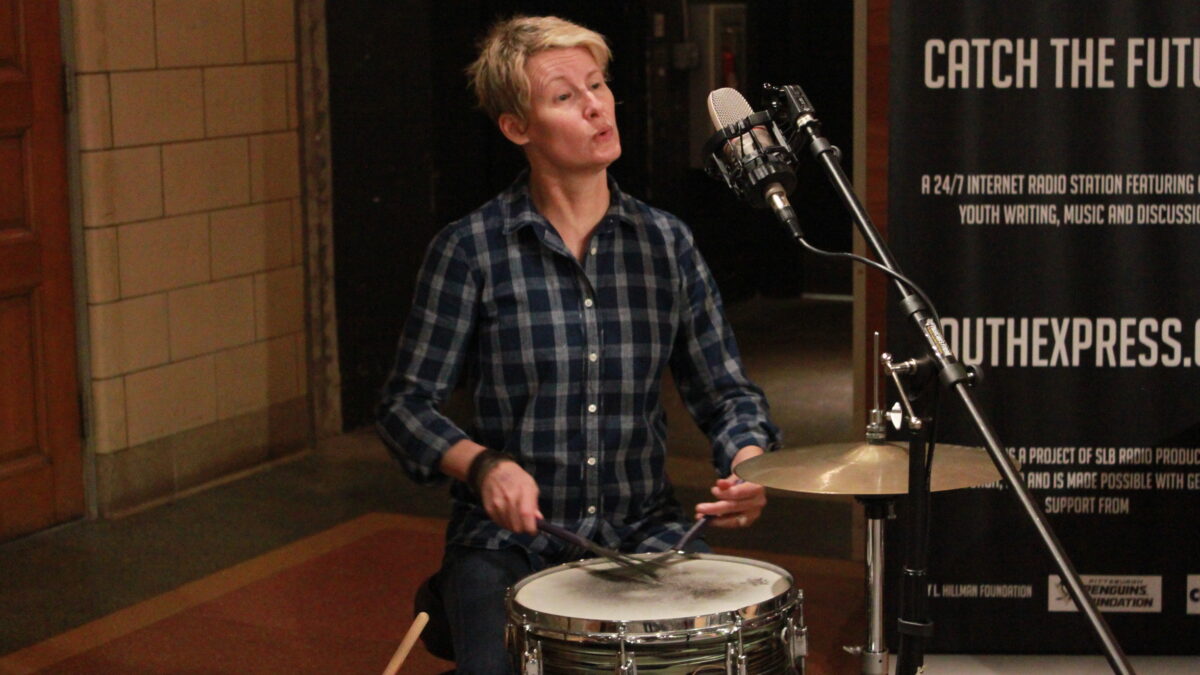 Adult playing drums outside a radio studio