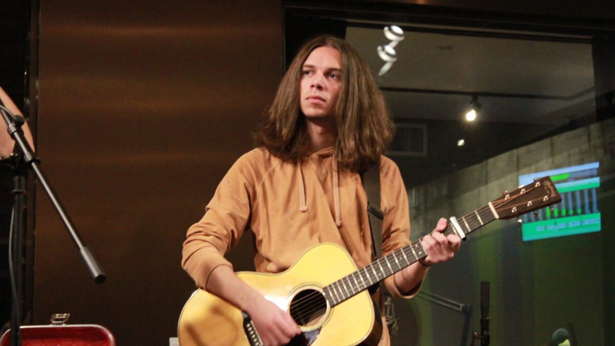 Adult playing guitar outside a radio studio