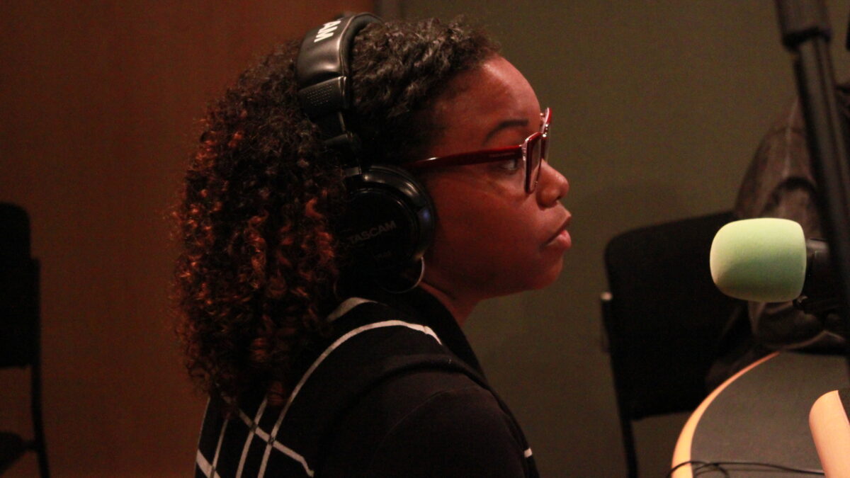 Teen wearing glasses and headphones speaking into a microphone in a radio studio