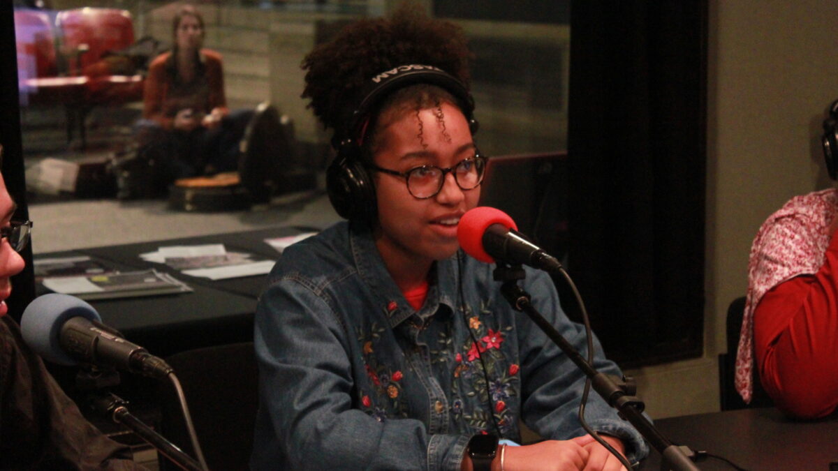 Teen wearing headphones speaking into a microphone in a radio studio