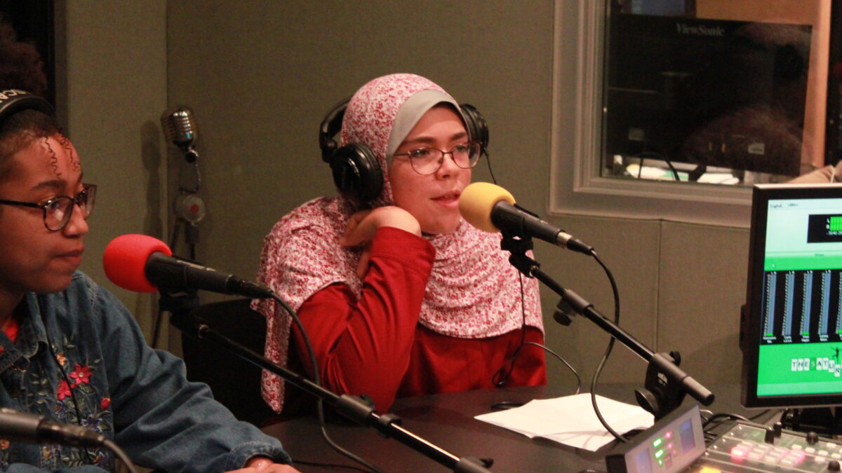 Two teens wearing headphones and speaking into microphones in a radio studio