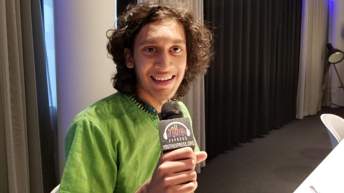 Young adult holding a microphone and smiling in profile