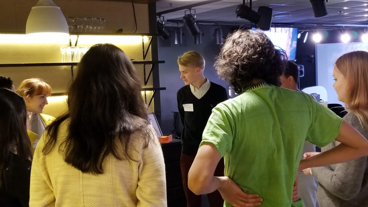 Eight young adults standing in a circle having a discussion