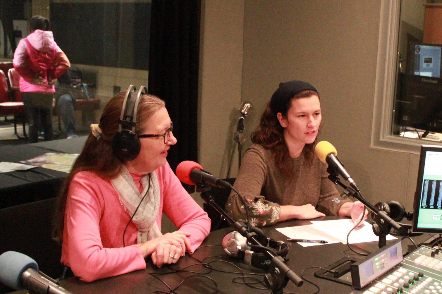 Two adults speaking into microphones being interviewed in a radio studio