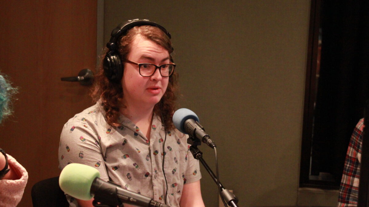 Teen wearing glasses and headphones speaking into a microphone in a radio studio