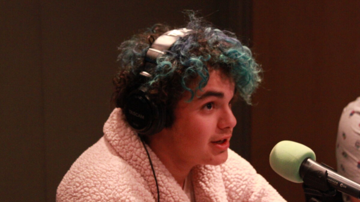 Teen wearing headphones speaking into a microphone in a radio studio