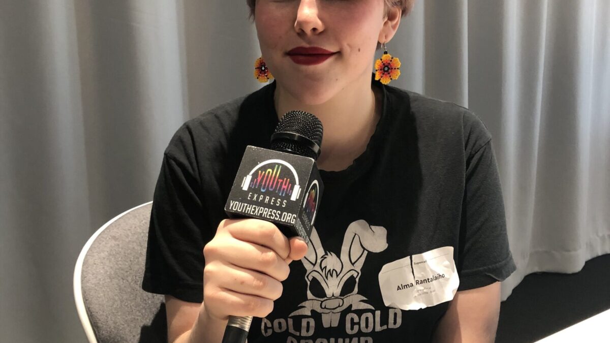 Adult sitting and holding a microphone smiling and posing in profile