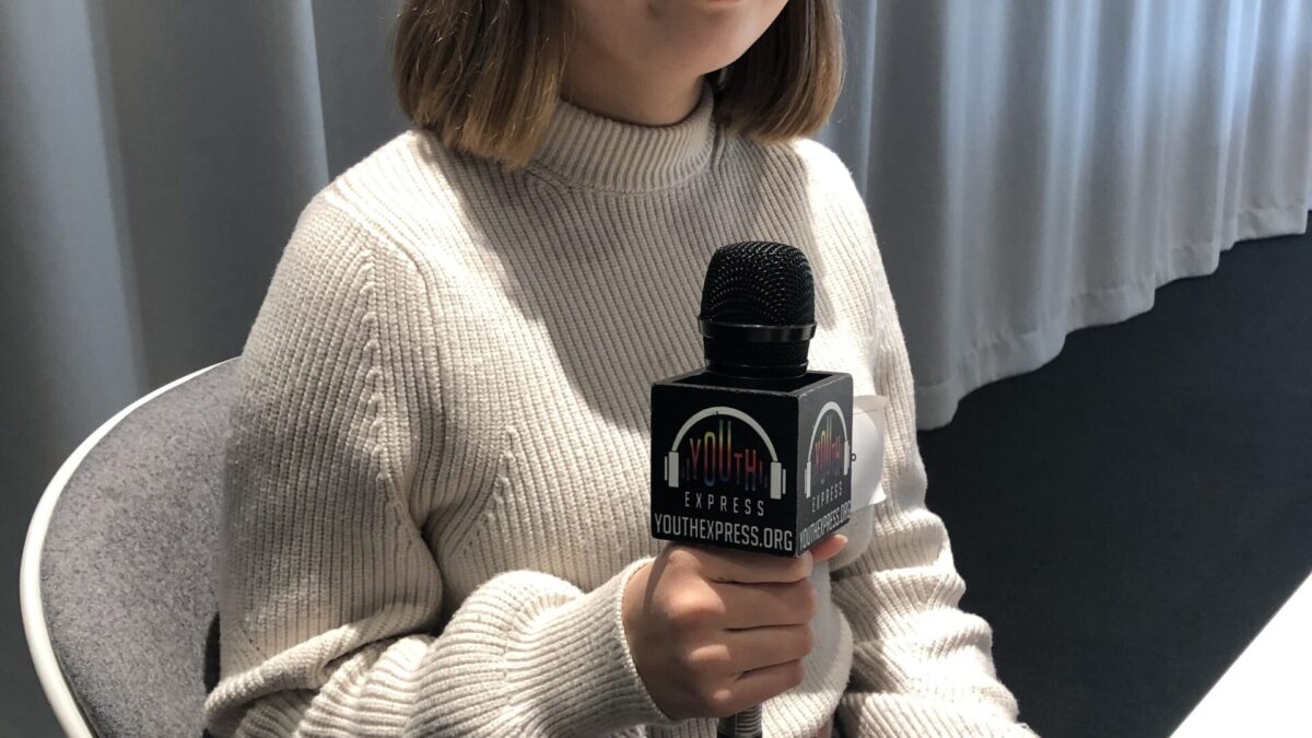 Person sitting and holding a microphone smiling and posing in profile