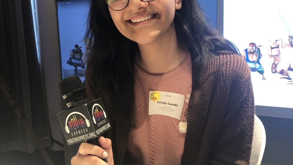 Adult wearing glasses and holding a microphone smiling in profile