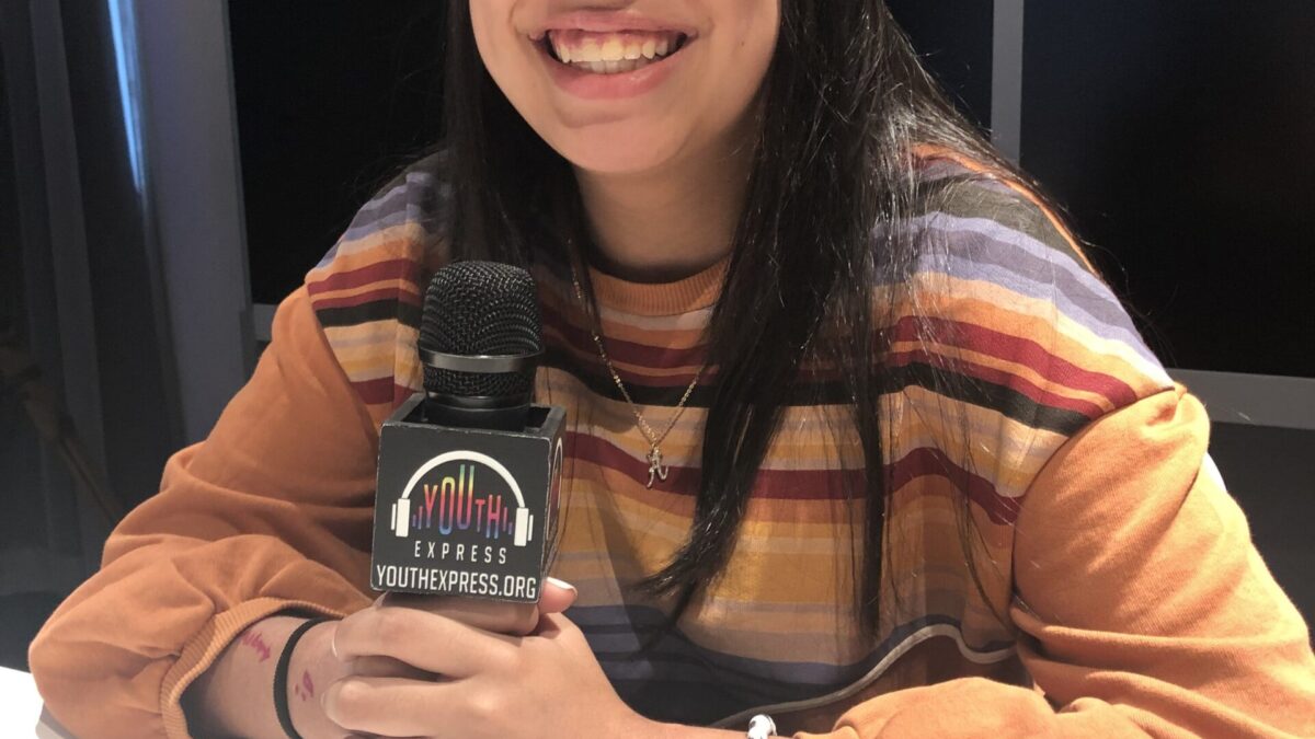 Adult sitting and holding a microphone smiling in profile
