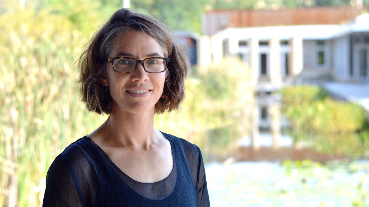 Adult with short brown hair and glasses smiling in profile