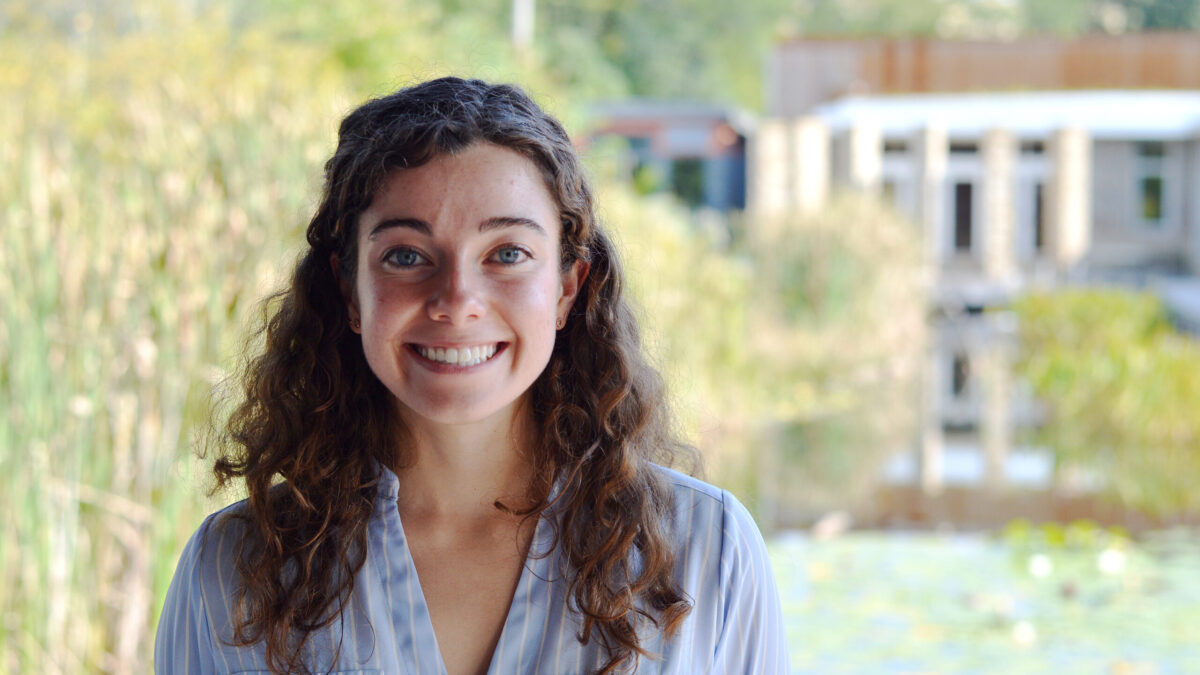 Adult with long brown curly hair smiling in profile