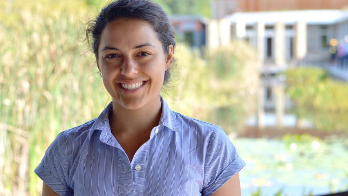 Adult with dark brown hair smiling in profile