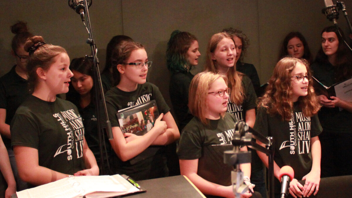 Twelve youth singing in a choir in a radio studio