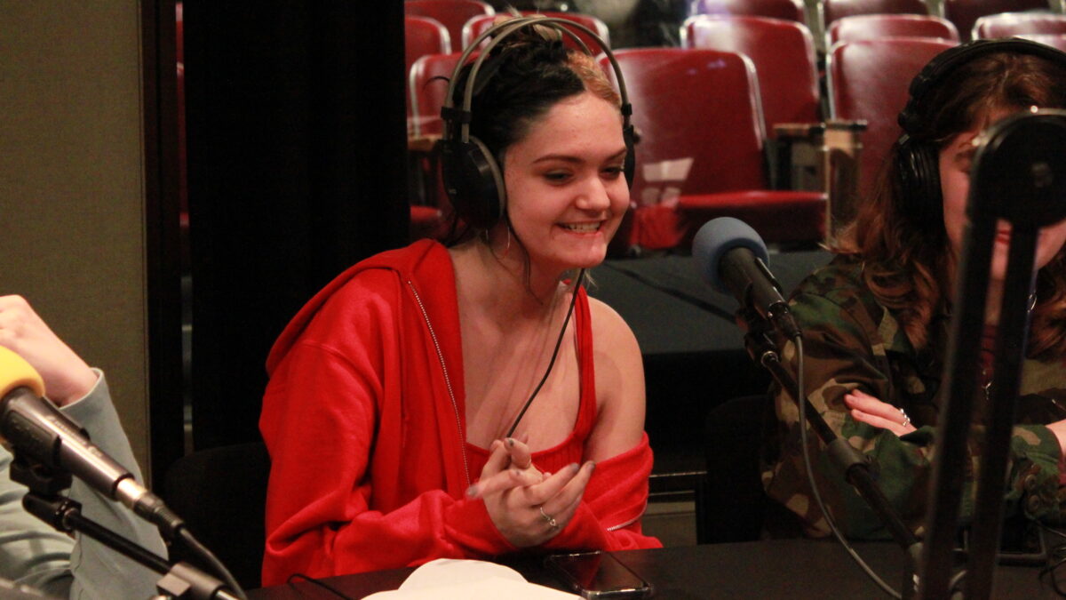 Teen wearing headphones speaking into a microphone in a radio studio