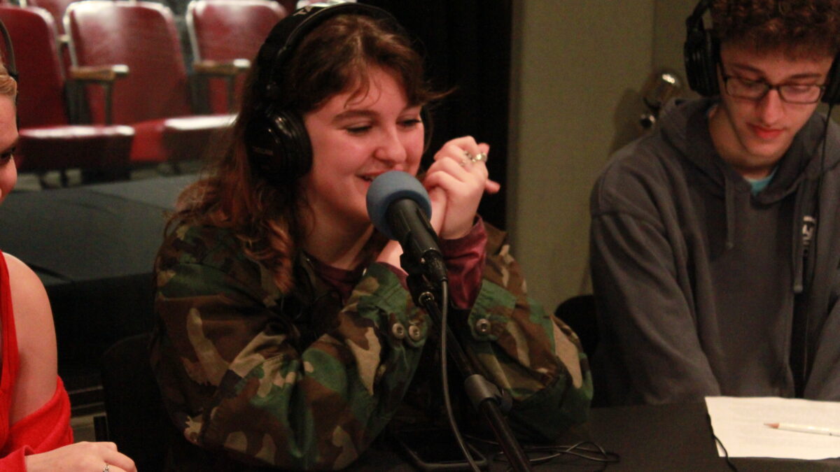 Teen wearing headphones speaking into a microphone in a radio studio