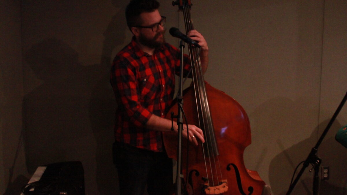 Adult playing upright bass in a radio studio