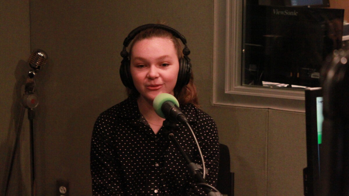 Teen wearing headphones and speaking into a microphone in a radio studio