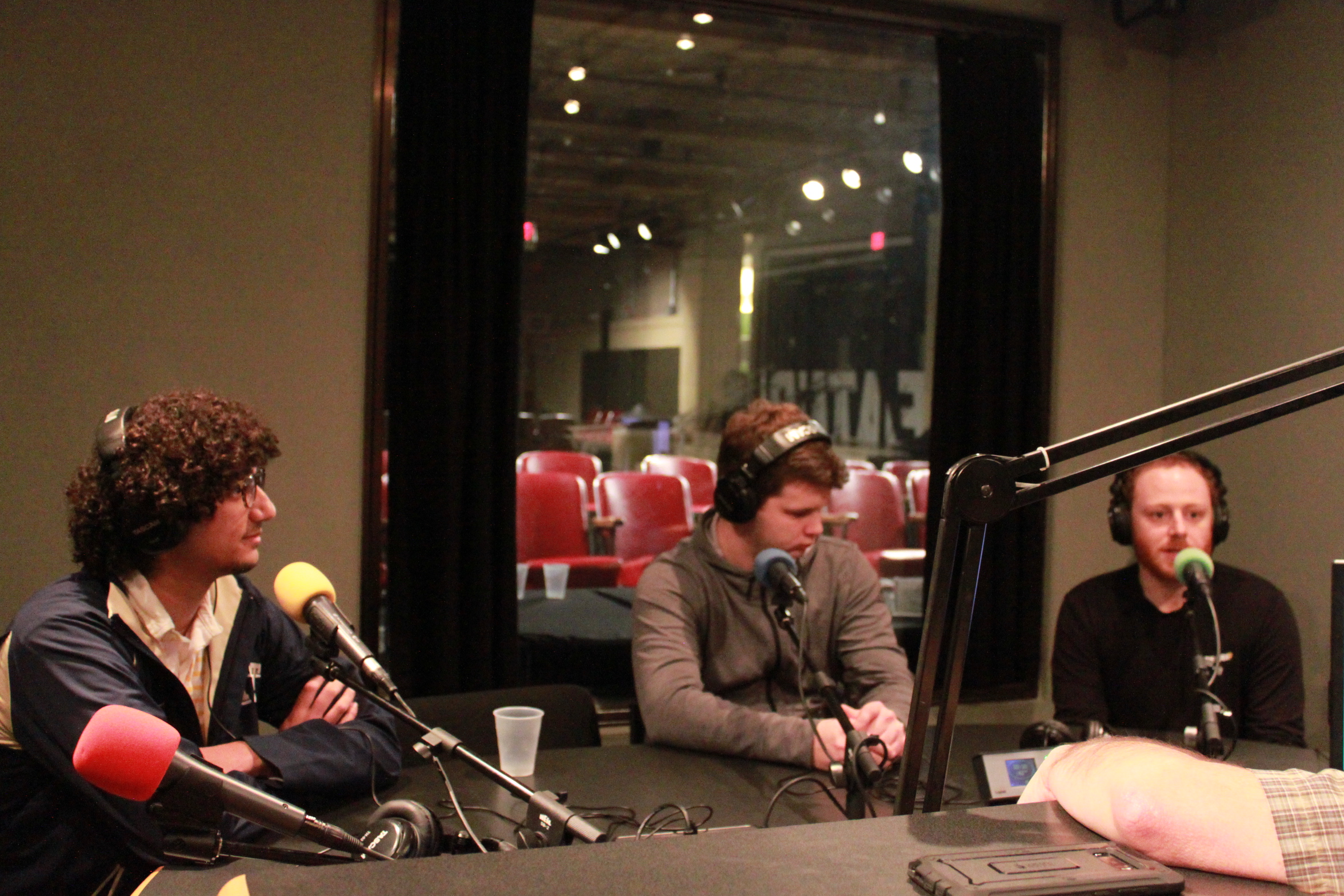 Two teens and one adult wearing headphones and speaking into microphones in a radio studio