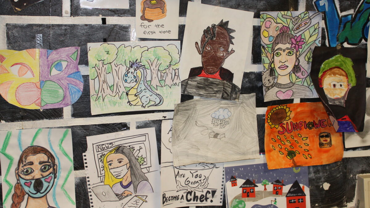 Multiple drawings displayed on a black brick wall