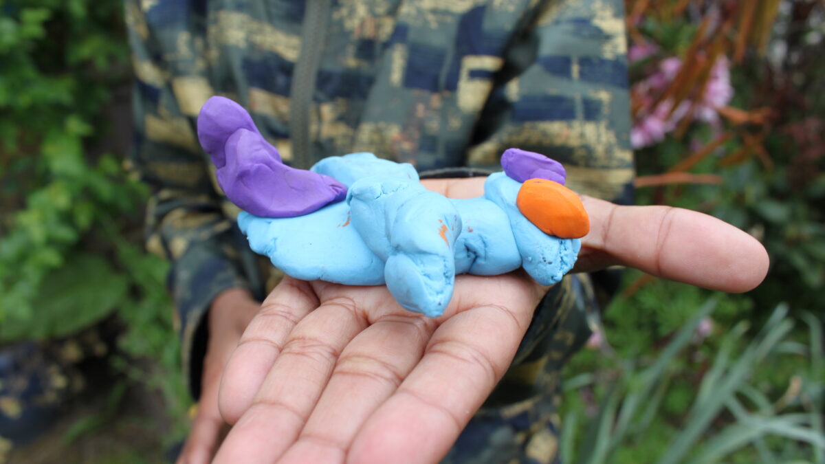 A person holding a light blue clay creature