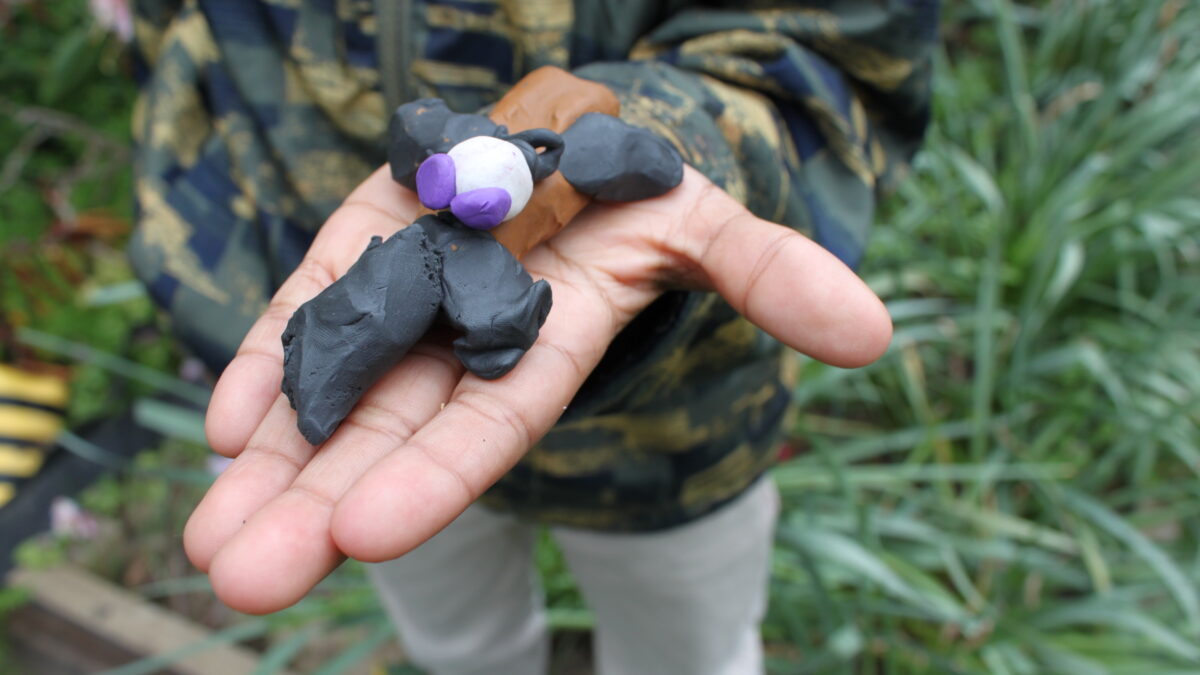A person holding a black clay creature