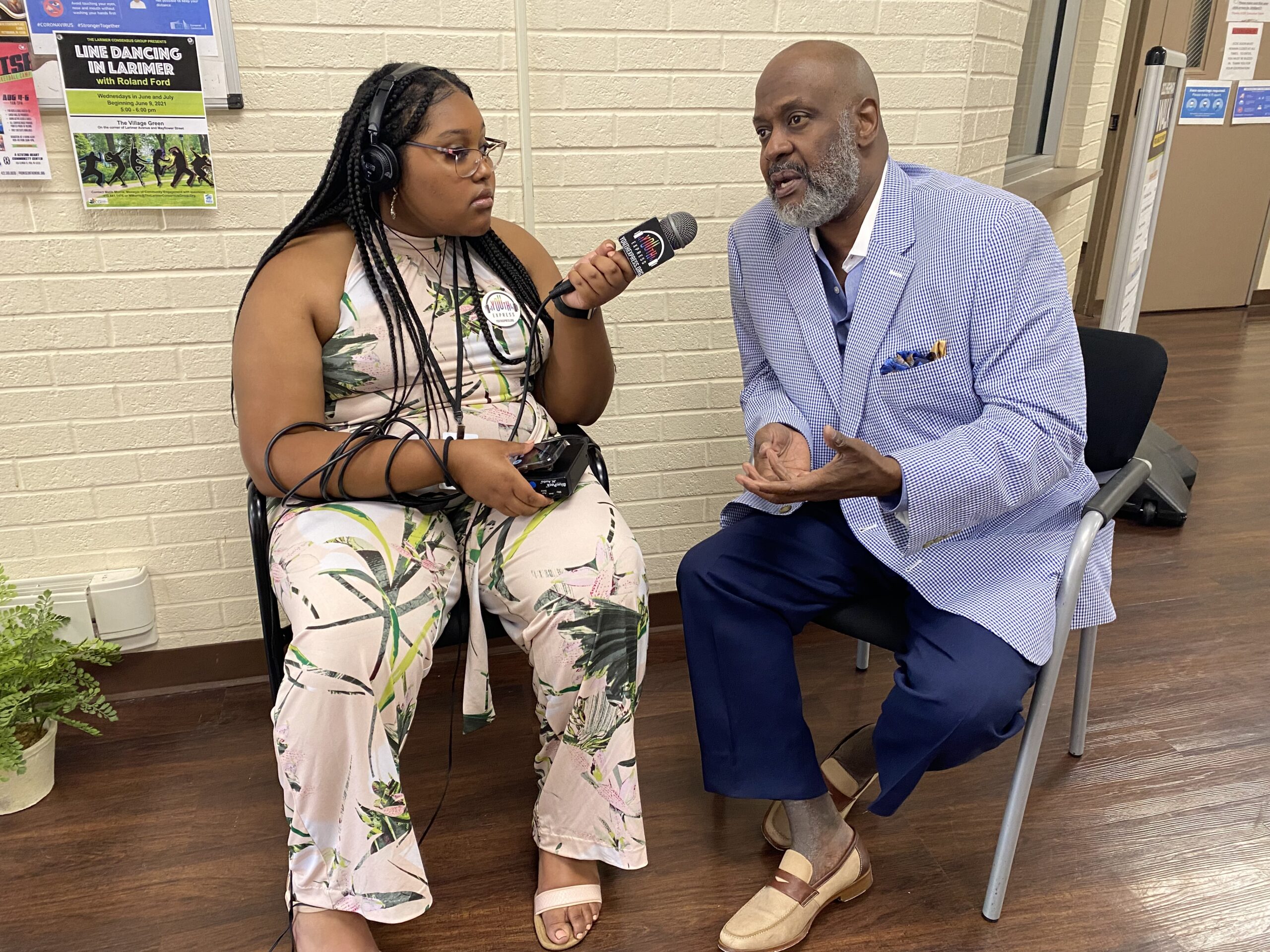 Teen wearing headphones using a portable recorder to interview an adult in a blue suit